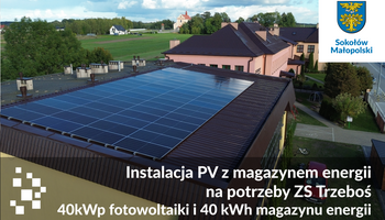 Widok z drona na dach sali gimnastycznej Zespołu Szk&oacute;ł nr 1 w Trzebosi z nową instalacją fotowoltaiczną. Na grafice informacja: instalacja PV z magazynem energii na potrzeby ZS Trzeboś &ndash; 40 kWp fotowoltaiki i 40 kWh magazynu energii.